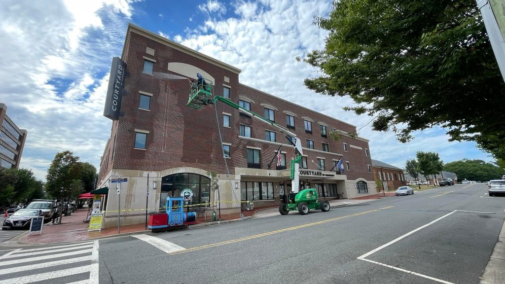 Commercial pressure washing company cleaning brick storefront in Charlotte NC - pressure washing hotel
